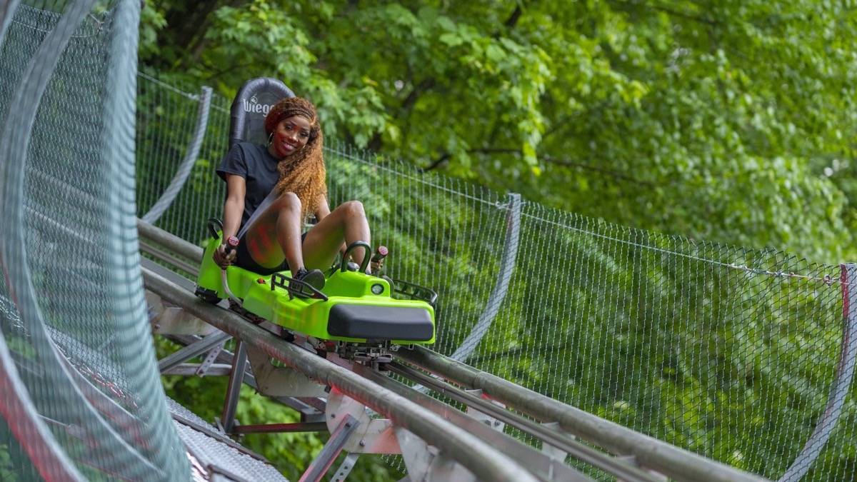 A girl in a black shirt on a coaster chair riding through an alpine coaster